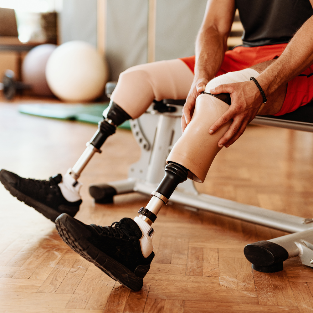 Sportler mit Beinprothese sitzt in einer Sporthalle.