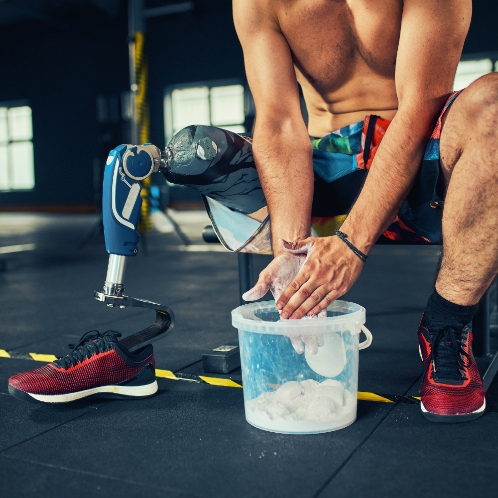 Sportler mit Beinprothese pudert seine Hände mit Magnesiumpulver.