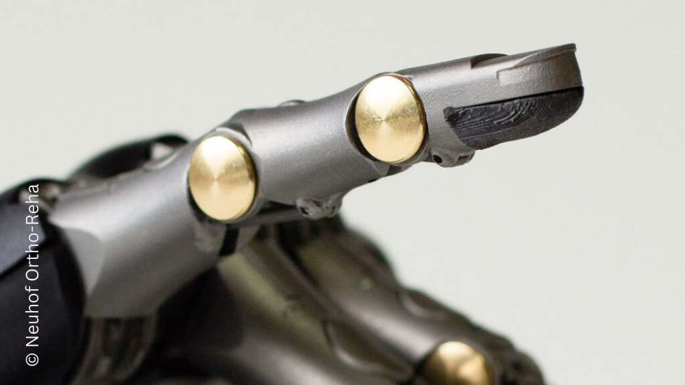 Nahaufnahme einer Fingerprothese mit goldenen Gelenken, die wie ein menschlicher Finger geformt ist.