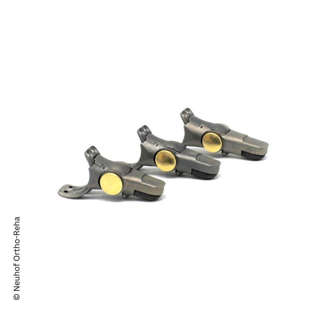 Drei metallische Fingerprothesen mit goldenen Gelenken, die auf einer weißen Oberfläche angeordnet sind.